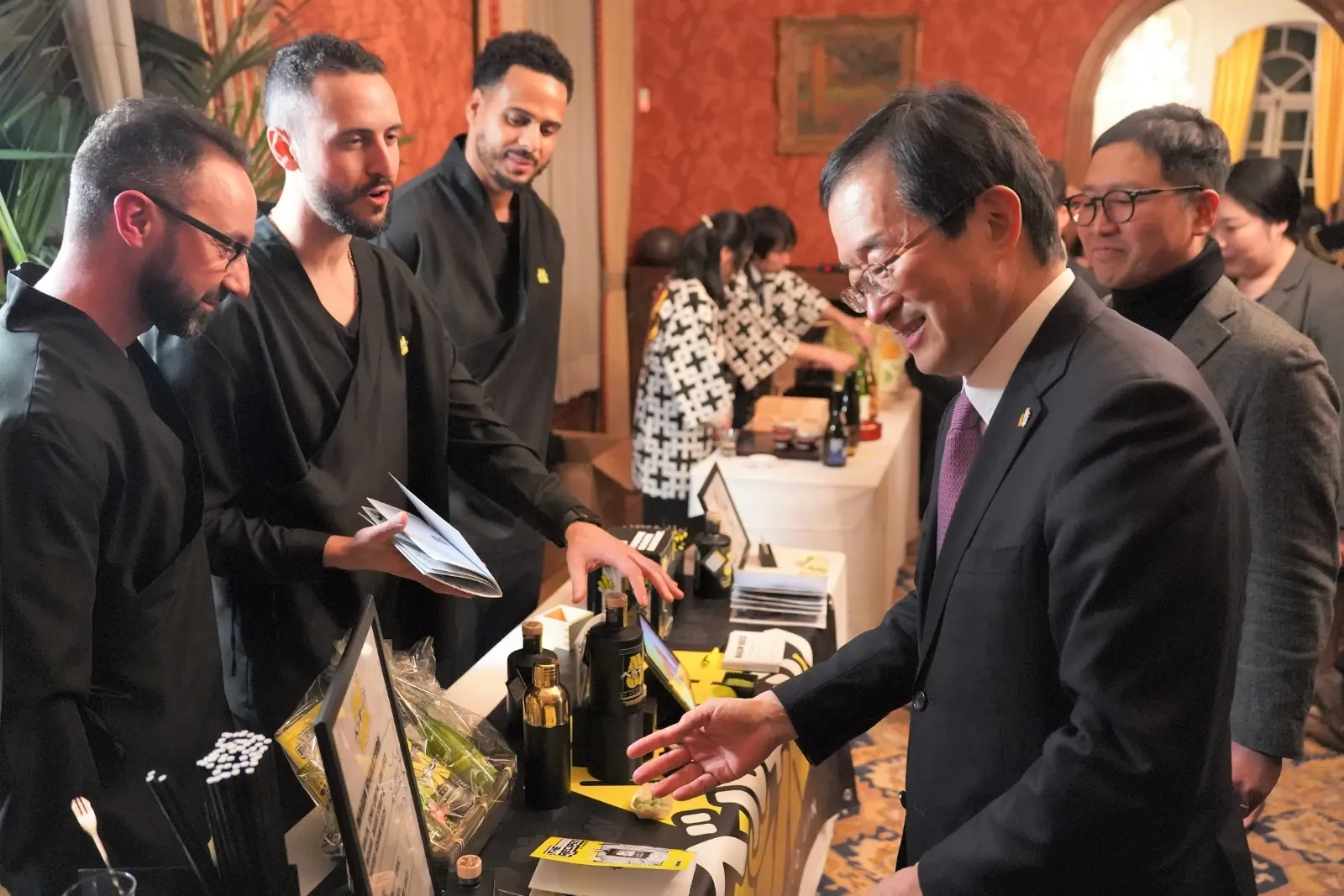The MaGin Team, in MaGin kimonos, presents MaGin Ki Yuzu to a guest from the Japanese delegation