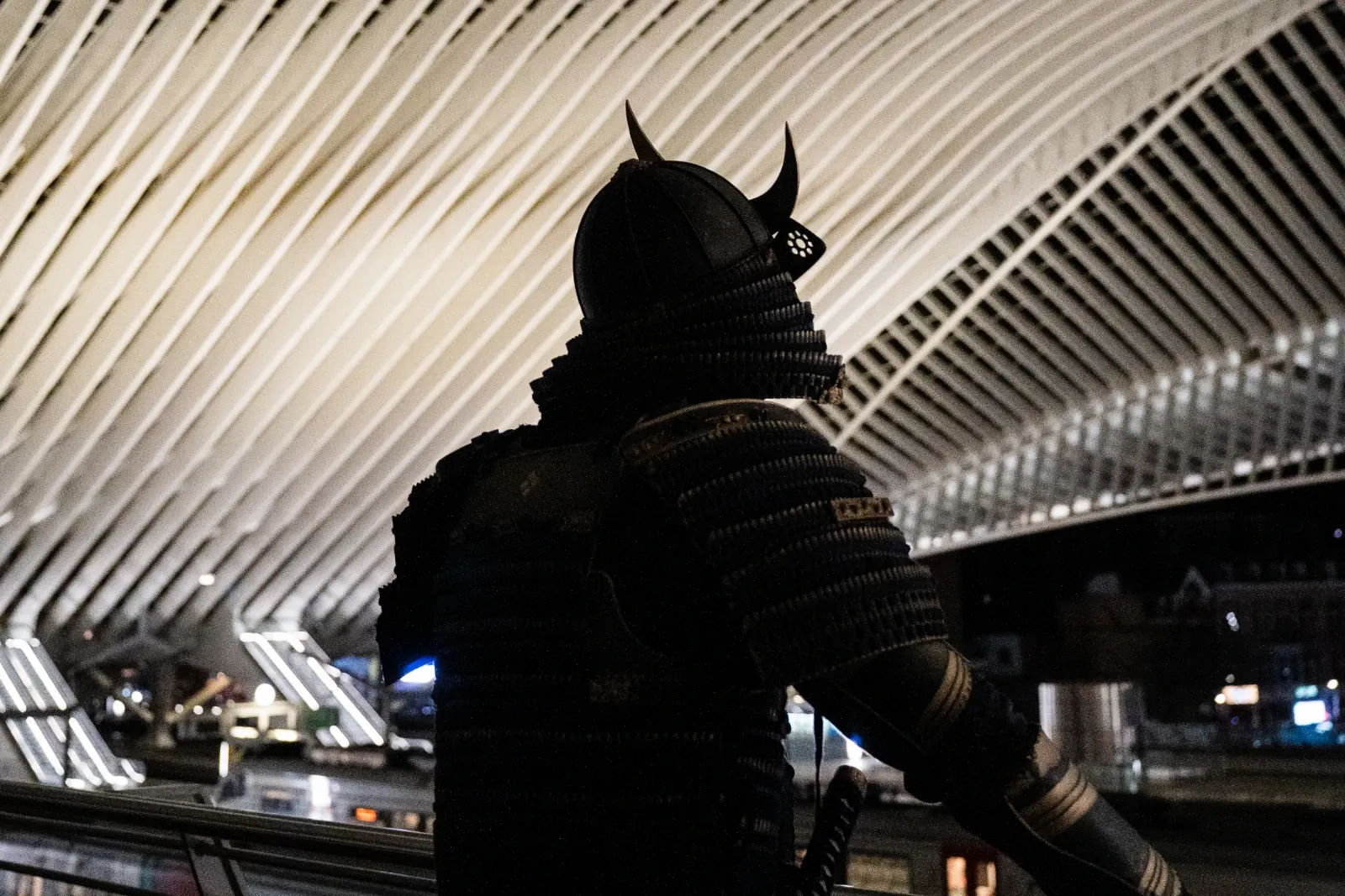 Le samouraï MaGin de dos sous la verrière de la gare de Liège-Guillemins