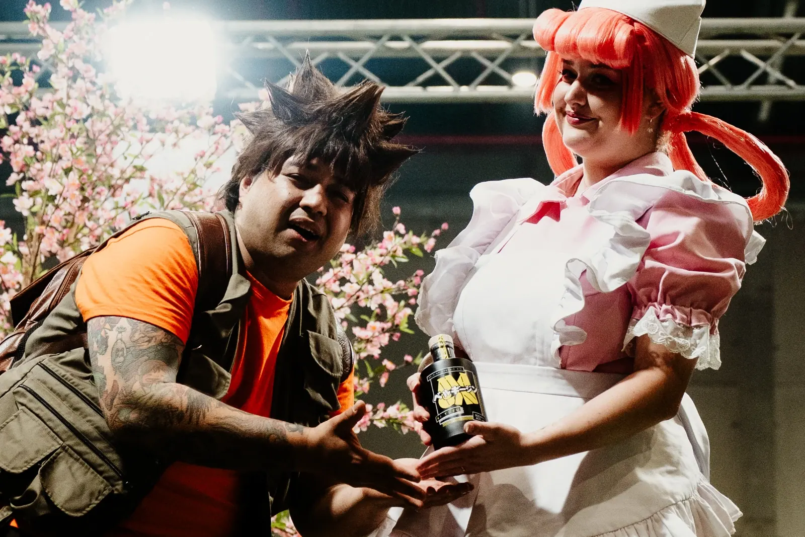 Deux cosplayeurs posent avec une bouteille MaGin Ki Yuzu devant des cerisiers en fleurs