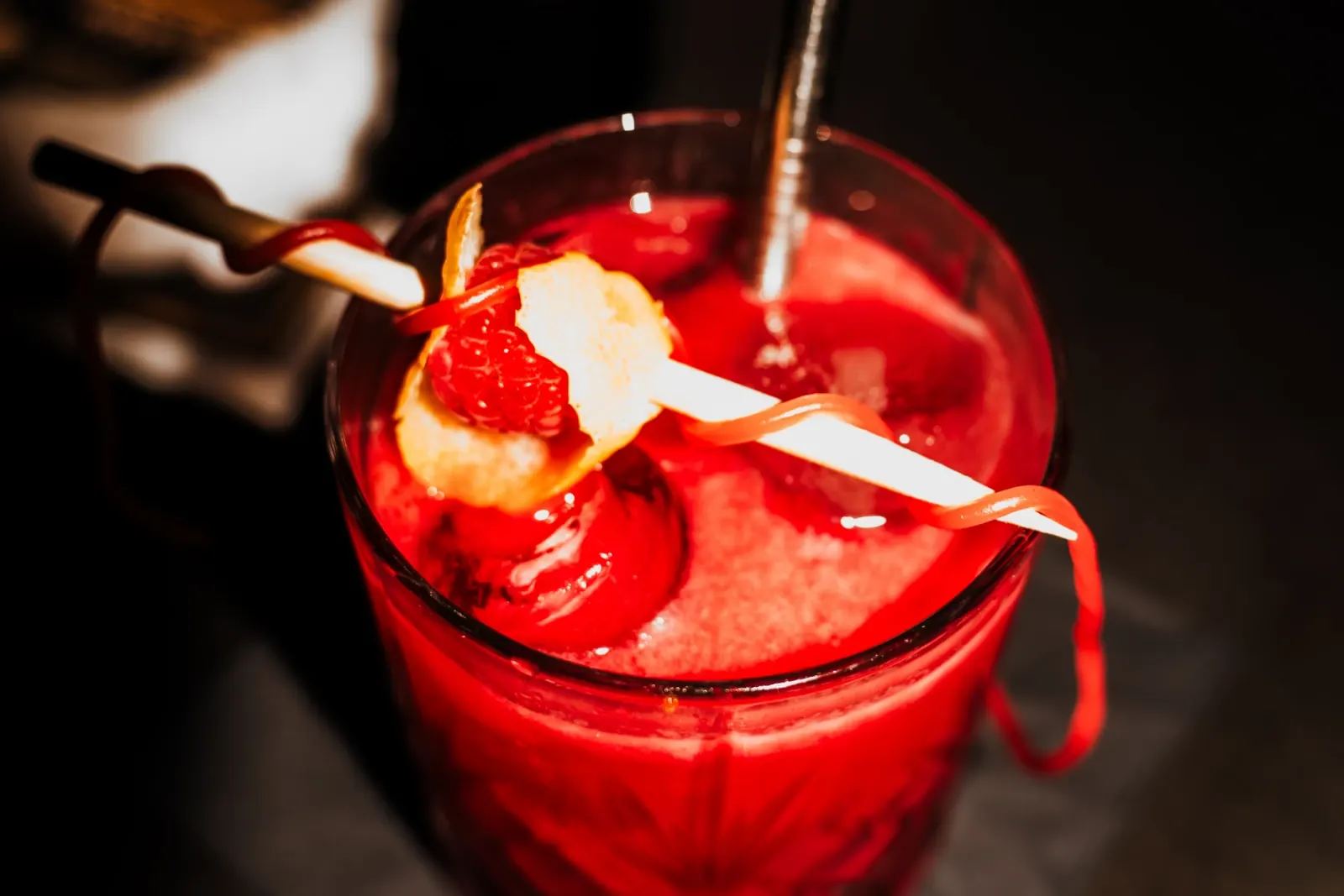 Gros plan sur le cocktail Akai Ito : framboise, zeste de citron et fil rouge