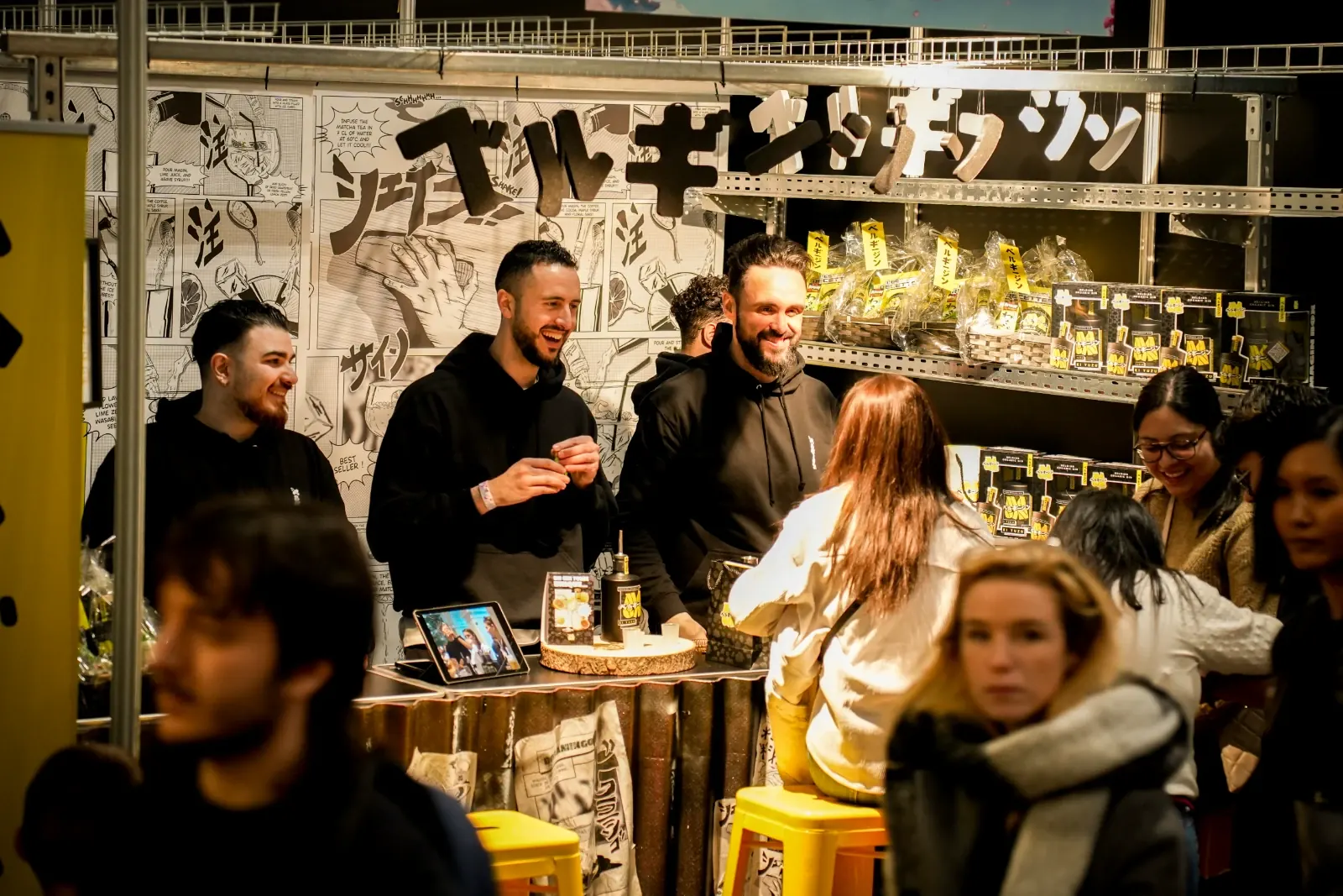 La Team MaGin sourit derrière son stand décoré de planches manga et de lettres en katakana